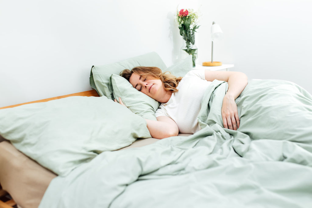 Vrouw ligt in bed onder Novaline Verzwaringsdeken