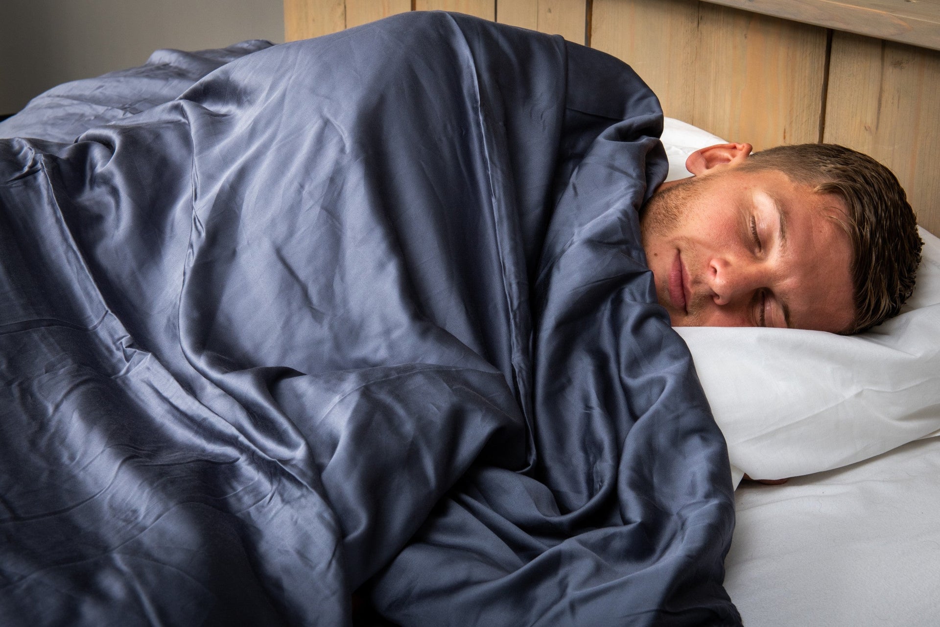 man onder verzwaringsdeken op bed