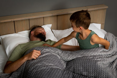 vader en zoon onder verzwaringdeken op bed